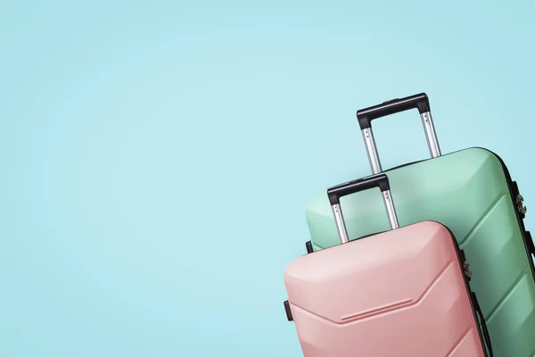 Two Suitcases on wheels on a blue background. Concept of travel, a vacation trip, a visit to relatives. Pink and Green color — Stock Photo, Image