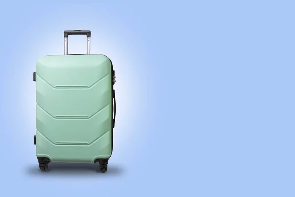 浅蓝色背景的轮子上的绿色的手提箱。旅行概念, 假期旅行, 探亲 — 图库照片