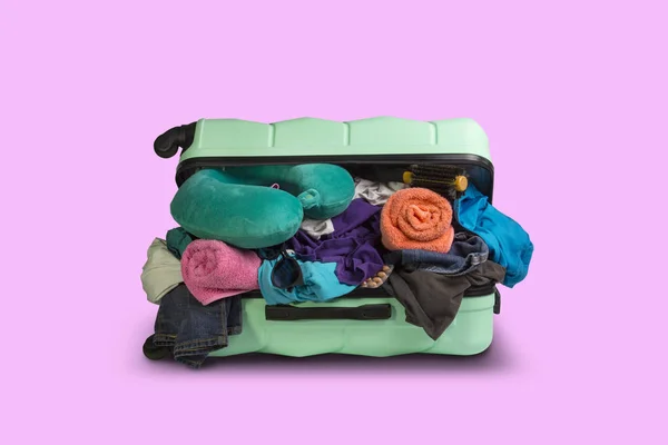 Kunststof koffer met wielen, vol van dingen op een roze achtergrond. Travel concept, vakantiereis, bezoek aan familie — Stockfoto