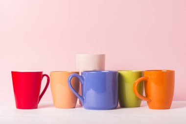 Bir sürü kahve veya çay pembe bir arka plan üzerinde renkli bardak. Bir dostu firma, büyük bir aile, bir fincan çay ya da kahve için toplantı arkadaşlar kavramı.