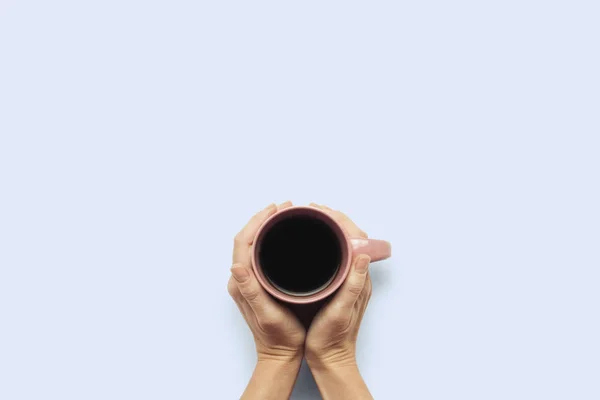 Dos manos sosteniendo una taza con café caliente sobre un fondo azul. Concepto de desayuno con café o té. Buenos días, noche, insomnio. Piso tendido, vista superior — Foto de Stock
