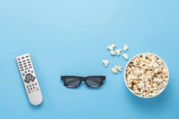 Cuenco con palomitas de maíz, gafas Imax, control remoto para TV sobre fondo azul. Concepto cine en casa, novedades del cine, ocio. Piso tendido, vista superior —  Fotos de Stock