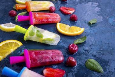 Homemade parlak çilek, kiraz, limon, portakal, limon ve nane tat ve dondurma yemeye koyu mavi zemin üzerine taze meyve ile buzlu şeker meyve