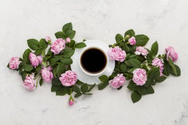 Hafif bir taş zemin üzerine siyah kahve ve pembe güller ile beyaz fincan. Düz yatıyordu, en iyi görünümü