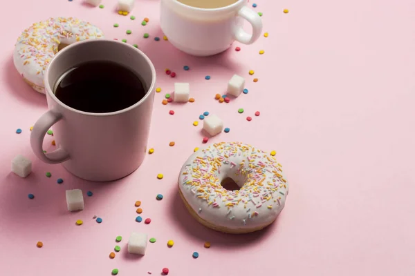 Bekers met koffie of thee, vers smakelijke zoete donuts op een roze achtergrond. Fast-food concept, bakkerij, Ontbijt, snoep, koffie shop. Plat lag, top uitzicht, kopie ruimte. — Stockfoto