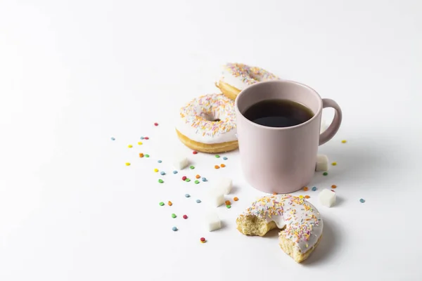 Taça rosa com café ou chá e donuts saborosos frescos, doces decorativos multicoloridos doces em um fundo branco. Conceito de padaria, doces frescos, delicioso café da manhã, fast food . — Fotografia de Stock