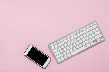Pembe arka planda klavye ve cep telefonu. İş konsepti. Düz yatıyordu, üst görünüm.