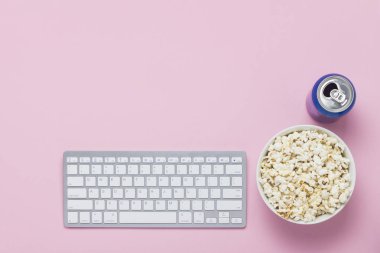 Klavye, bir içki ve pembe bir arka planda bir kase patlamış mısır ile olabilir. Film izleme kavramı, TV gösterileri ve Online gösterir. Düz yatıyordu, üst görünüm.