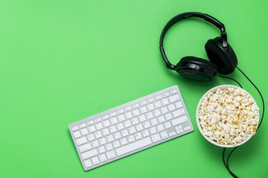 Klavye, kulaklık ve yeşil bir arka planda patlamış mısır bir kase. Film izleme kavramı, gösterileri, PS spor, Online Oyunlar. Düz yatıyordu, üst görünüm.