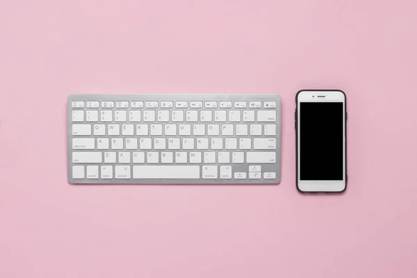 Teclado y teléfono móvil sobre fondo rosa. Concepto de negocio. Piso tendido, vista superior . — Foto de Stock