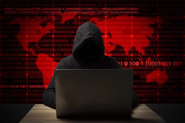 Hacker in a jacket with a hood with a laptop sits at the table. Added identity theft icons, account hijacking, bank data theft and world map — Stock Photo, Image