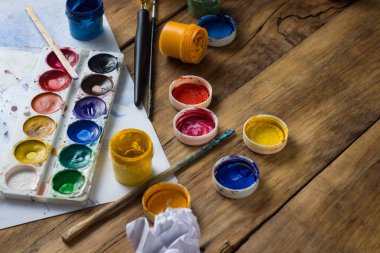 Sanatçının Akrilik boyalar, guaş ve suluboya, fırçalar ve yaprak kağıt ahşap arka plan üzerinde çalışma alanı. Yaratıcı sınıf kavramı