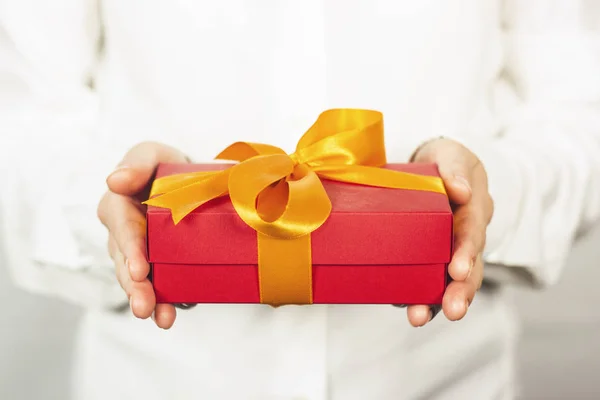 The girl in a white shirt holds a gift. The concept of celebrating a birthday, a new year, christmas, wedding. Receiving a gift. — Stock Photo, Image