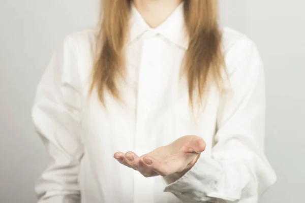 Una chica con una camisa blanca sostiene la palma de su mano hacia arriba. Taza de Pose . — Foto de Stock