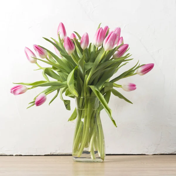 Стеклянная ваза и букет розовых тюльпанов на фоне белой каменной стены. Концепция праздника и начало весны . — стоковое фото