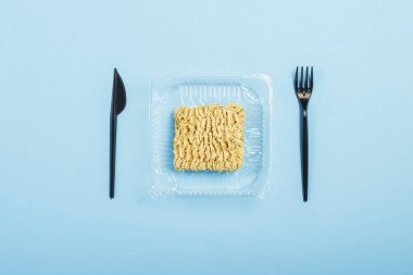 Mavi bir arka plan üzerinde Asya anlık erişte ve plastik tek kullanımlık yemekler. Kolaylık gıdalar, fast food, abur cubur kavramı. Düz döşeme, üst görünüm.