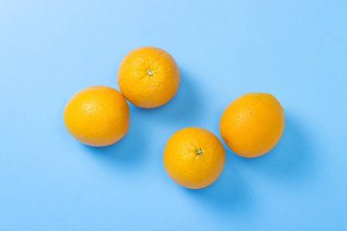 Mavi arka plandaki portakallar. Tropikal meyve kavramı, tatil ve seyahat, diyet ve kilo kaybı. Düz döşeme, üst görünüm.