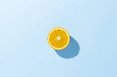 Cut half of orange on a blue background. Minimalism. Concept of tropics, healthy eating, vitamins. Flat lay, top view. clipart