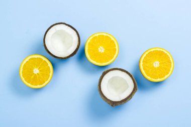 Mavi bir arka plan üzerinde kesilmiş portakal ve hindistan cevizi. Tropikal meyve kavramı, tatil ve seyahat, diyet ve kilo kaybı. Düz döşeme, üst görünüm.