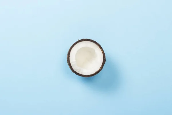 Mitad coco sobre un fondo azul. Minimalismo. Concepto de trópico, alimentación saludable. Piso tendido, vista superior . — Foto de Stock