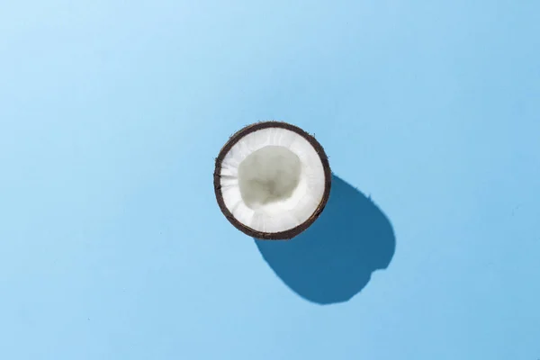 Demi noix de coco sur fond bleu. Minimalisme. Concept de tropiques, une alimentation saine. Couché plat, vue du dessus . — Photo