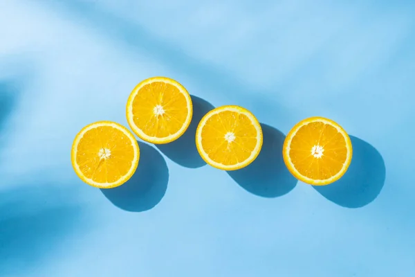 Naranjas sobre fondo azul bajo luz natural con sombras. Luz dura. Concepto de dieta, alimentación saludable, descanso en los trópicos, vacaciones y viajes, vitaminas. Piso tendido, vista superior . — Foto de Stock