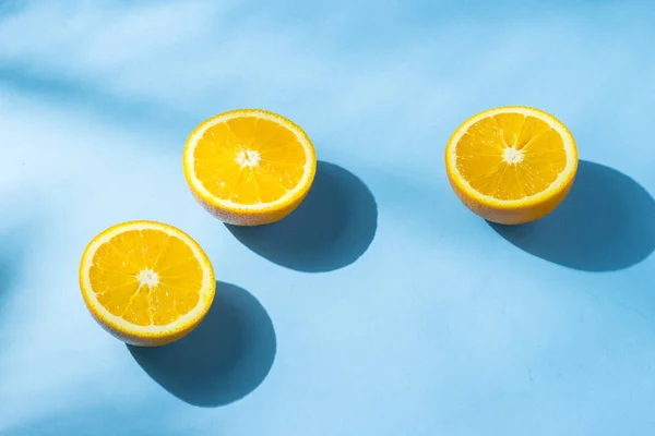 Naranjas sobre fondo azul bajo luz natural con sombras. Luz dura. Concepto de dieta, alimentación saludable, descanso en los trópicos, vacaciones y viajes, vitaminas . — Foto de Stock
