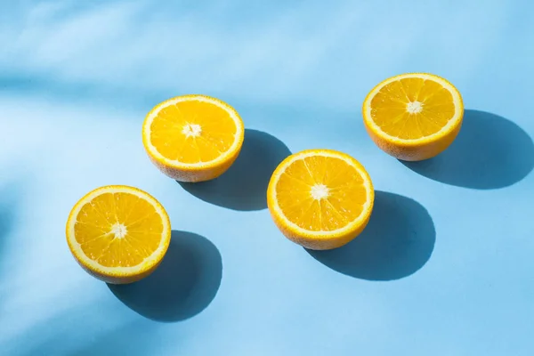 Naranjas sobre fondo azul bajo luz natural con sombras. Luz dura. Concepto de dieta, alimentación saludable, descanso en los trópicos, vacaciones y viajes, vitaminas . — Foto de Stock