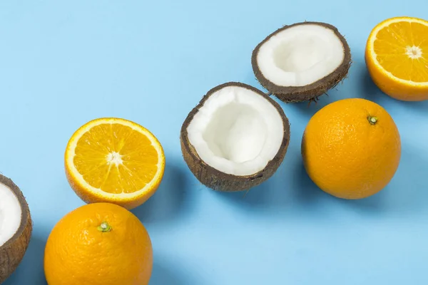 Corte naranja y coco sobre un fondo azul. Concepto de frutas tropicales, vacaciones y viajes, dieta y pérdida de peso . — Foto de Stock