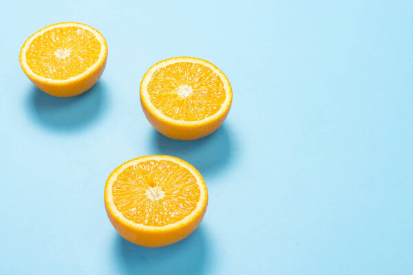 Half cut orange on a blue background. Concept of tropical fruits, vacation and travel, diet and weight loss.