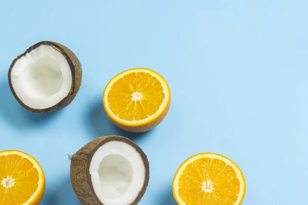 Corte naranja y coco sobre un fondo azul. Concepto de frutas tropicales, vacaciones y viajes, dieta y pérdida de peso . — Foto de Stock