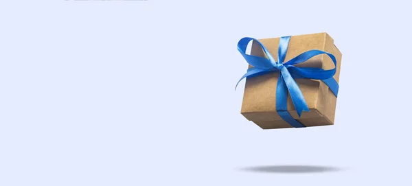Flying gift box on a light blue background. Holiday concept, gift, sale, wedding and birthday. Banner. — Stock Photo, Image