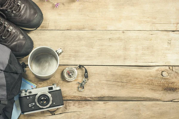 Botas, mochila, brújula y otros equipos de camping sobre un fondo de madera. El concepto de senderismo en las montañas o el bosque, el turismo, el descanso de la tienda, el campamento. Piso tendido, vista superior . — Foto de Stock