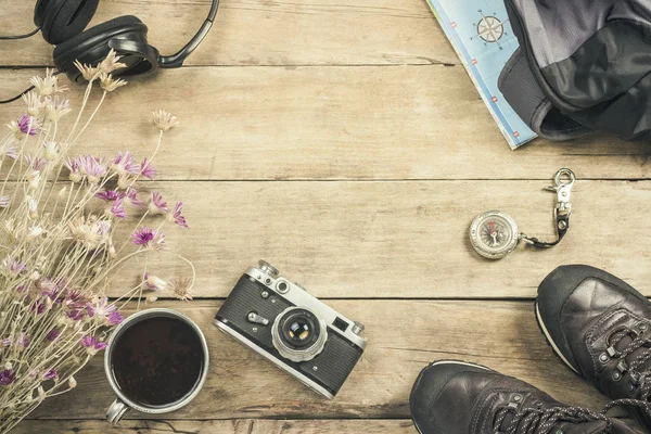 Boots, backpack, compass and other camping gear on a wooden background. The concept of hiking in the mountains or the forest, tourism, tent rest, camp. Flat lay, top view.