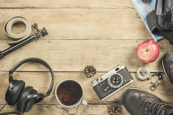 Boots, backpack, compass and other camping gear on a wooden background. The concept of hiking in the mountains or the forest, tourism, tent rest, camp. Flat lay, top view.