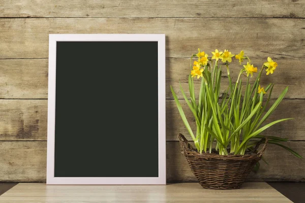 Clear Board and a vase with Spring Flowers on a wooden background. The concept of the beginning of spring, holiday. Copy space.