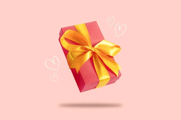 Caja de regalo voladora sobre un fondo rosa claro con corazones. Concepto de vacaciones, regalo, venta, boda y cumpleaños . —  Fotos de Stock