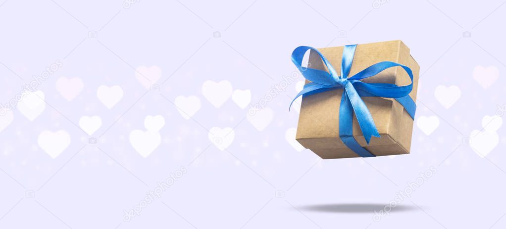 Flying gift box on a light background with heart shaped bokeh. Holiday concept, gift, sale, wedding and birthday. Banner.