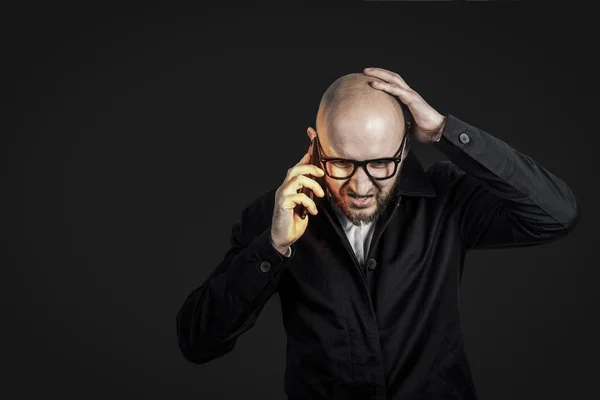 Hombre de negocios con una cara malvada en una camisa blanca y un manto oscuro habla y grita por teléfono sobre un fondo oscuro. Estrés conceptual, malos negocios, ira, demasiadas llamadas telefónicas . — Foto de Stock