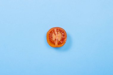 Mavi bir arka plan üzerinde yarım Domates kesin. Vitamin kavramı, yaz mevsimi, kahvaltı. Düz döşeme, üst görünüm.