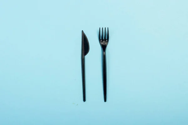 Black Disposable plastic tableware and appliances for food. Concept plastic, harmful, environmental pollution, stop plastic. Flat lay, top view.