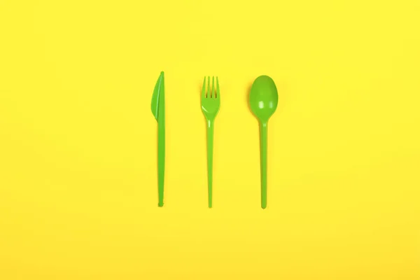 Vihreä Kertakäyttöiset muoviset astiat ja laitteet ruokaa keltaisella pohjalla. Haarukka, lusikka ja veitsi. Käsite muovi, haitallinen, ympäristön saastuminen, pysäytä muovi. Tasainen, ylhäältä . — kuvapankkivalokuva