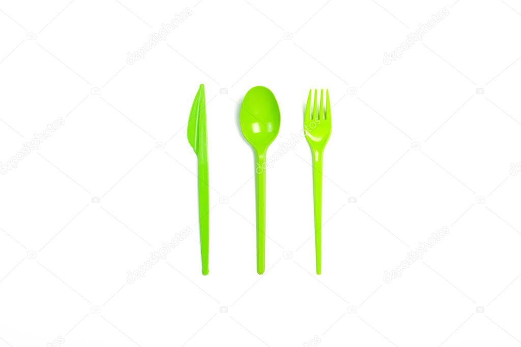Green Disposable plastic tableware and appliances for food on a white background. Fork, spoon and knife. Concept plastic, harmful, environmental pollution, stop plastic. Flat lay, top view.