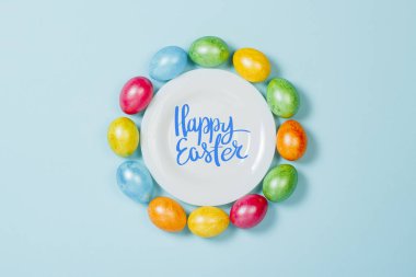 Mavi arka plandaki tabakta Paskalya yumurtaları. Paskalya'yı kutlama konsepti. Düz döşeme, üst görünüm