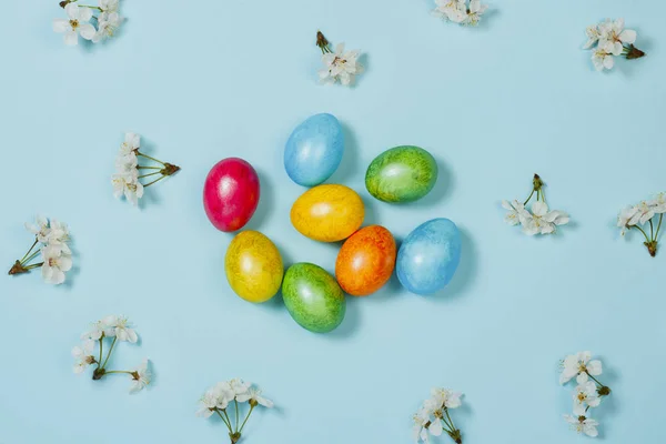 Ovos de Páscoa e flores de primavera em um fundo azul. Conceito de celebrar a Páscoa. Deitado plano, vista superior — Fotografia de Stock