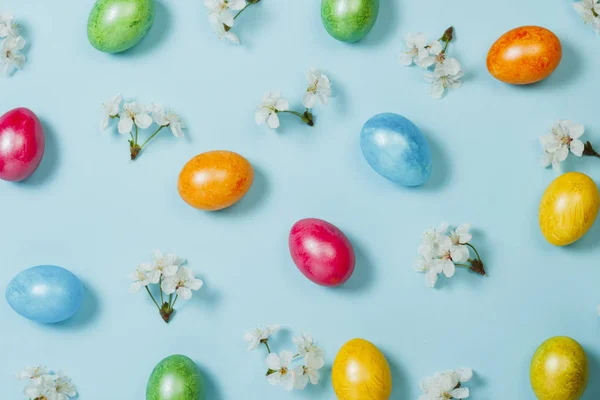 Ovos de Páscoa e flores de primavera em um fundo azul. Conceito de celebrar a Páscoa. Deitado plano, vista superior — Fotografia de Stock