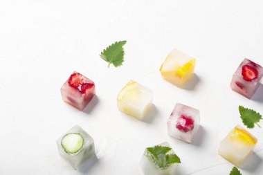 Beyaz taş arka planda meyve ve nane yaprakları ile buz küpleri
