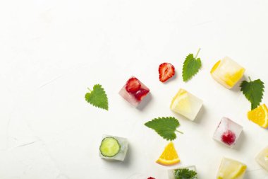 Beyaz taş arka planda meyve ve nane yaprakları ile buz küpleri