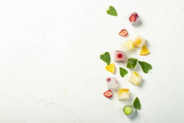 Beyaz taş arka planda meyve ve nane yaprakları ile buz küpleri