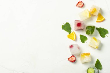 Beyaz taş arka planda meyve ve nane yaprakları ile buz küpleri